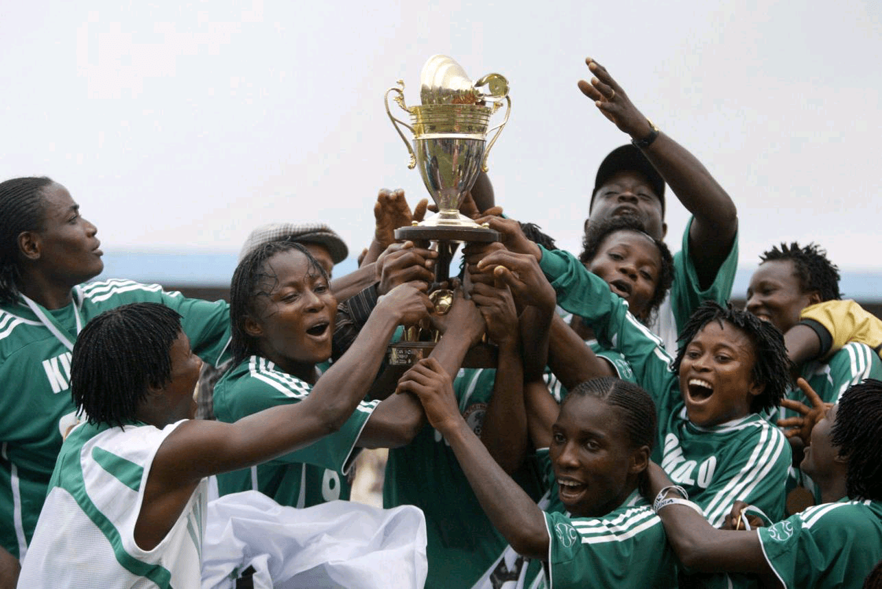 AS Roma women's team celebrating their Serie A trophy with Nigerian players holding the cup